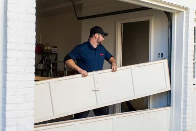 Garage door repair tech removing a garage door section